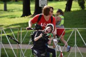 Mother assisting her child on an adapted trike.